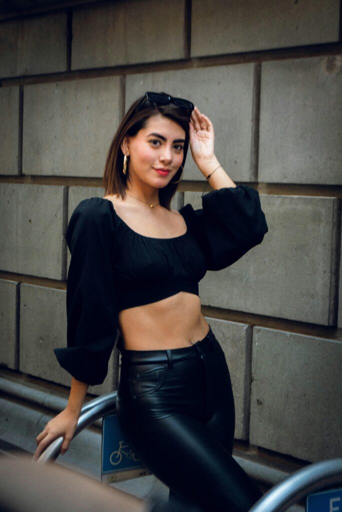 Fashionable woman posing confidently with a modern urban backdrop, showcasing style and elegance.